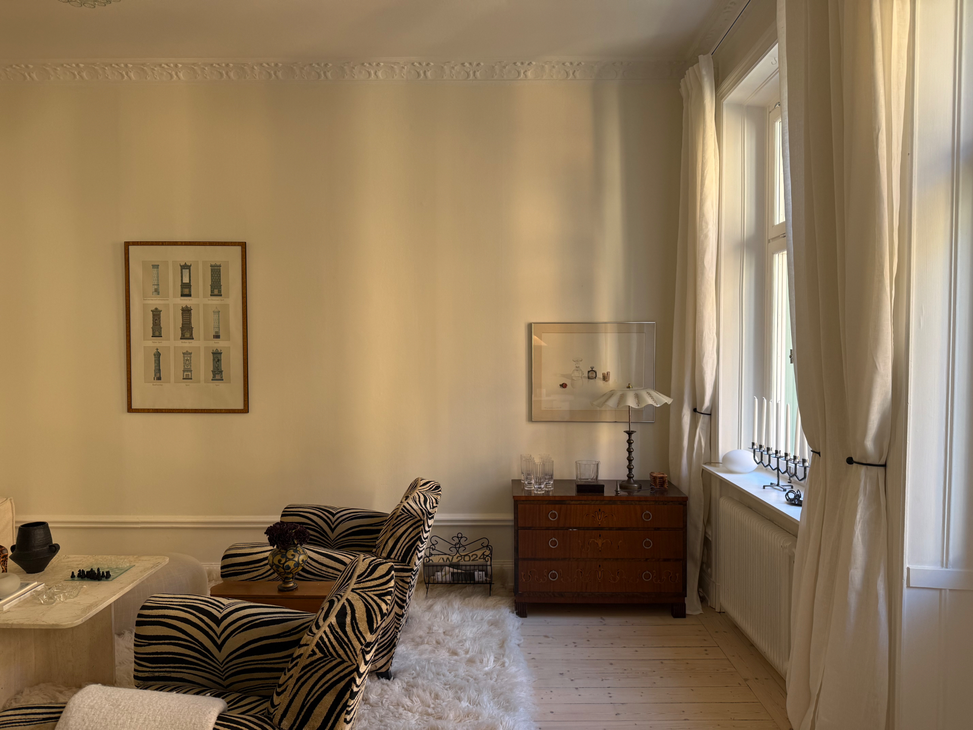 Vintagehem med zebramönstrade fåtöljer, mahognybyrå och jugendlampa i varmt kvällsljus